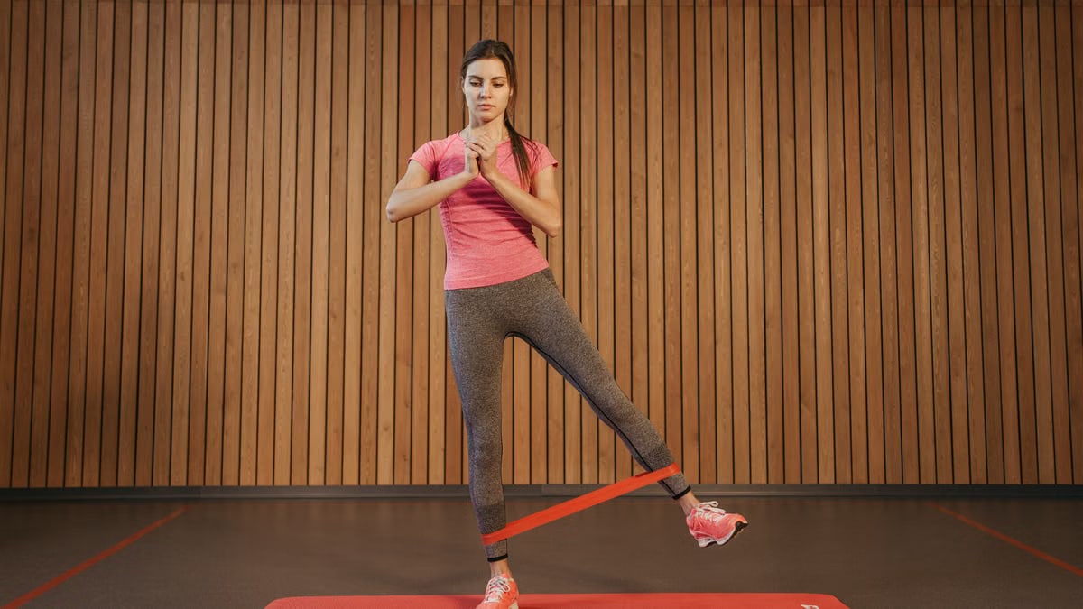 A woman performs leg exercises with a resistance band at a gym, promoting fitness and healthy living.